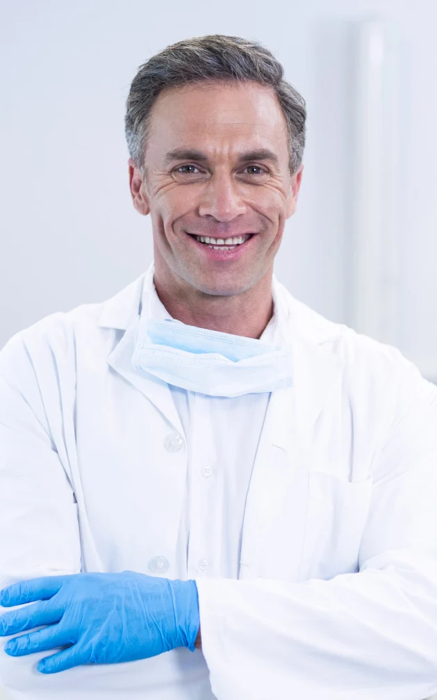 smiling dentist standing with arms crossed P55SNTE 1
